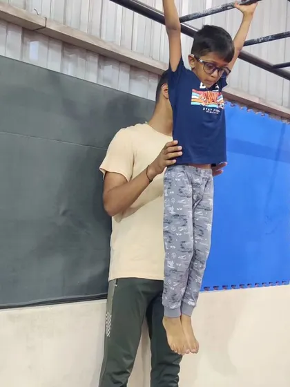 This image is a duplicate of 46, showing a coach providing gentle support to a young student on the bars. This encouragement helps our youngest athletes feel safe.