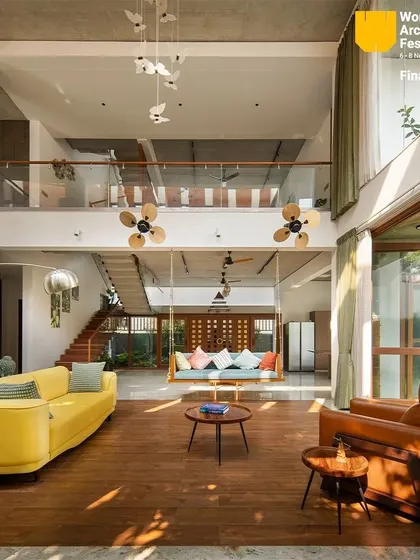 The living area, with its traditional swing and modern sofas, looks out onto the garden through floor-to-ceiling glass doors, creating a perfect blend of comfort and nature.