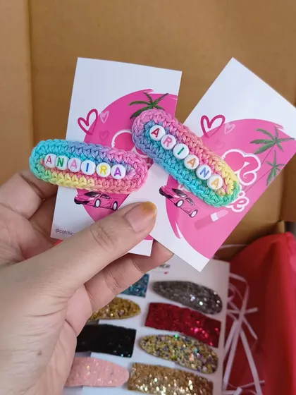 A pair of our rainbow name clips for Anaisha and Ariana, held up to show the detail. The bright colors and personalized touch make these a favorite.