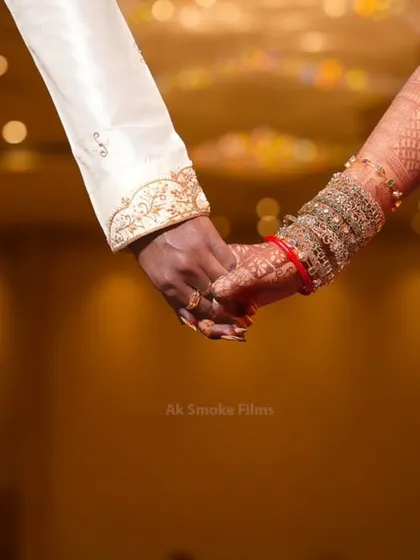 A close-up shot of the couple holding hands, symbolizing their union. The focus is on the traditional attire and henna.