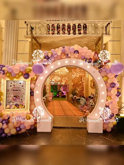 A stunning circular entrance arch adorned with pastel and gold balloons and a personalized welcome sign, creating a grand entryway for a first birthday party.