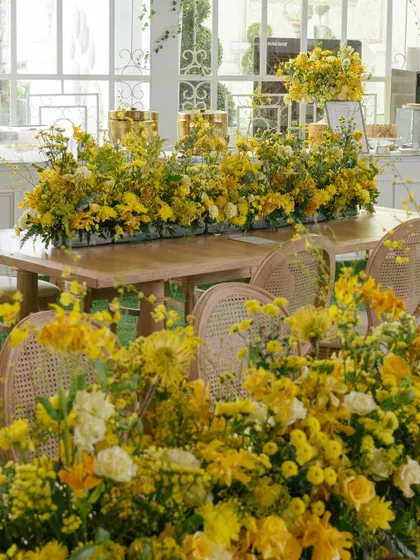 Tables overflowing with arrangements of yellow flowers, creating a lush, garden-like feel within the Haldi venue.