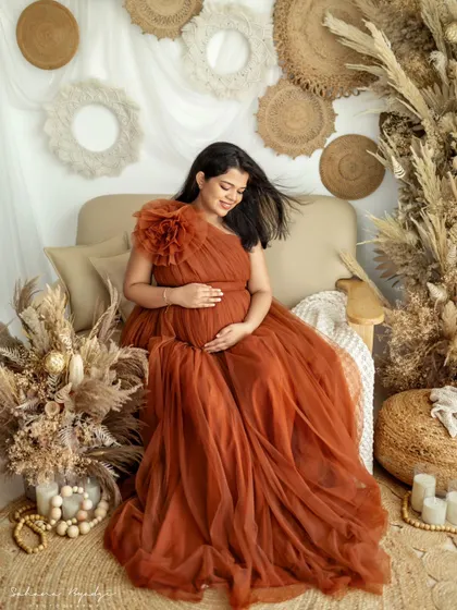 A moment of quiet contemplation. The mom-to-be sits peacefully in our boho-themed setup, her hand on her belly, looking absolutely serene and beautiful.