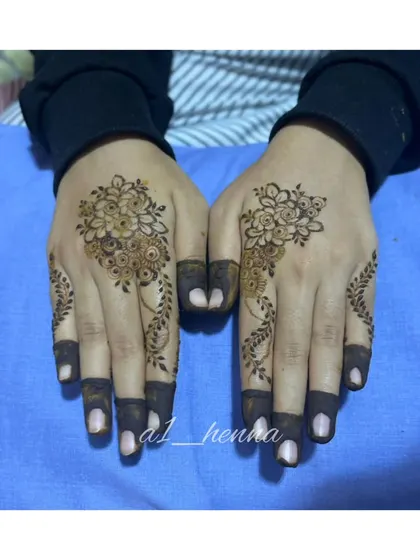 A minimal floral cluster on the back of the hand with delicate vine details on the fingers.