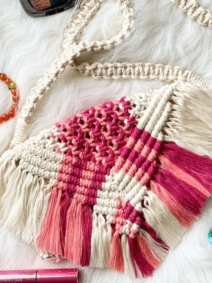 This fringed sling bag is a true boho statement piece. The design features a beautiful geometric pattern in shades of pink against a cream background, styled here with a few daily essentials.