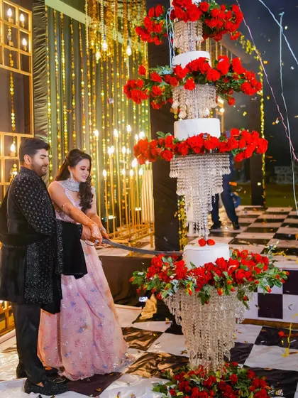 The grand cake-cutting ceremony, featuring a magnificent chandelier-style cake adorned with red roses. We capture these spectacular details that make your celebration unique.
