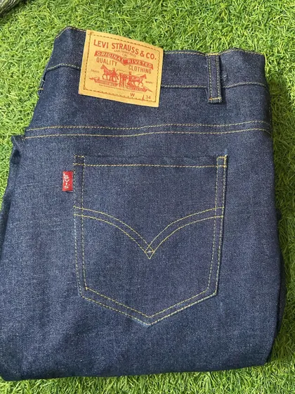 A freshly stitched pair of classic dark wash jeans, featuring the iconic leather patch and red tab detail, made to the client's exact waist and length.