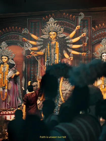 Faith is unseen but felt. A devotee stands before the magnificent idol of Goddess Durga, a moment of personal connection amidst the large crowd.
