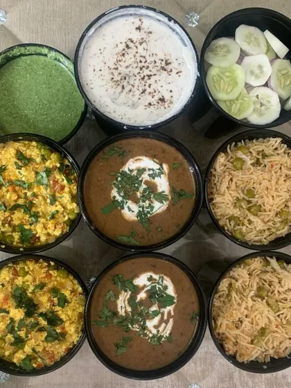 A beautiful display of a bulk order before packing. This order included Dal Makhni, Paneer Bhurji, Veg Pulao, Raita, and salad, served in individual bowls.