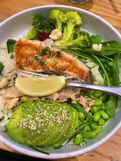 A perfect healthy dinner bowl. A piece of salmon cooked in butter, served with greens, steamed broccoli, edamame, and creamy avocado. This meal is balanced with protein, healthy fats, and fiber.