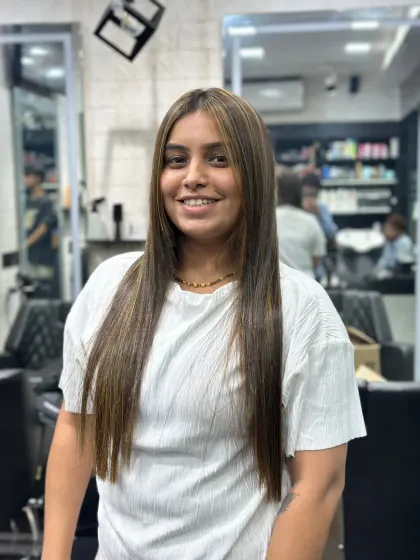 The client's happy smile says it all. Her straight hair with soft, golden-brown highlights is a timeless look that is both professional and stylish.