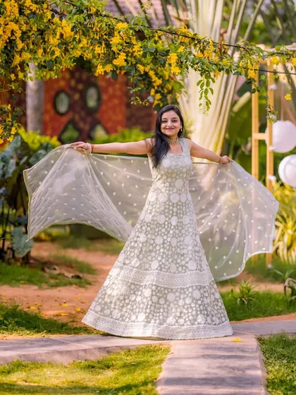 A beautiful, candid moment of a bride twirling in her elegant lehenga. The natural garden setting and the soft light create a very dreamy and romantic feel.