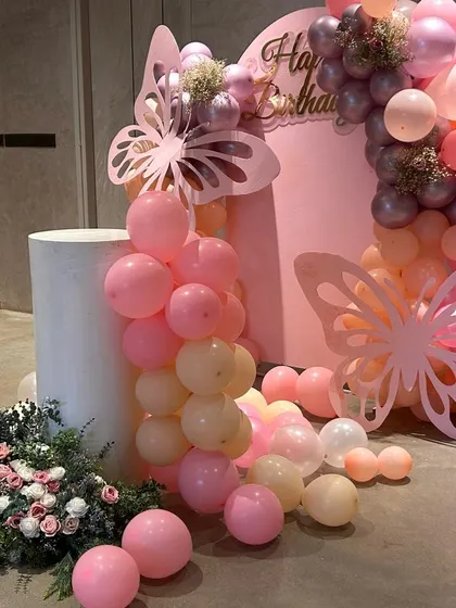 Another perspective of the main decor area, showing how all the elements come together. The white plinth stands ready for the cake, surrounded by cascading balloons and fresh flowers.
