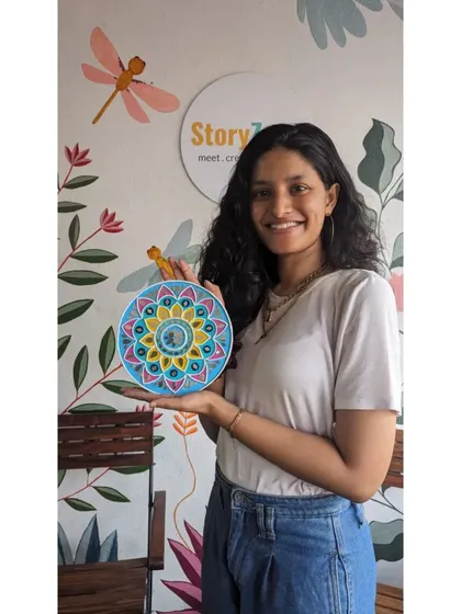 A happy participant holding her completed Lippan artwork against the backdrop of our studio wall. She was able to finish this entire decorative plate, from color choice to mirror placement, during a single session.