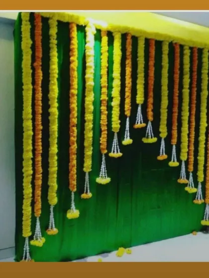 A simple backdrop of hanging marigold garlands against a dark green curtain. This is a budget-friendly option that still provides a traditional and festive look.