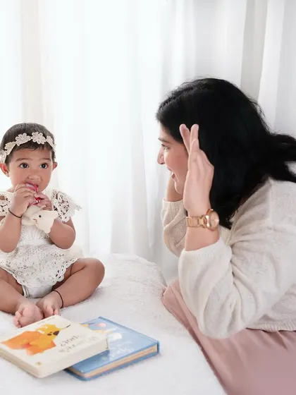 A mother playing peek-a-boo with her baby. My sessions are child-led, which means we always make time for games and fun.