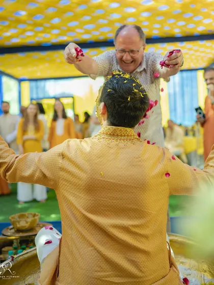 A father's joyful blessing, showering his son with flowers during the Haldi ceremony.