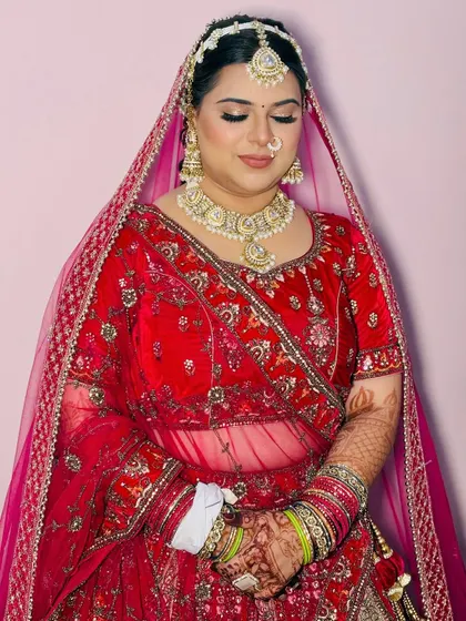 A close-up of the bride's makeup, showing the flawless base and soft pink lip color that perfectly complements her red outfit.