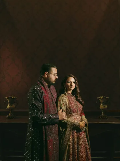 A classic portrait of the couple. The groom's dark, printed sherwani perfectly complements the bride's rich, jewel-toned anarkali.