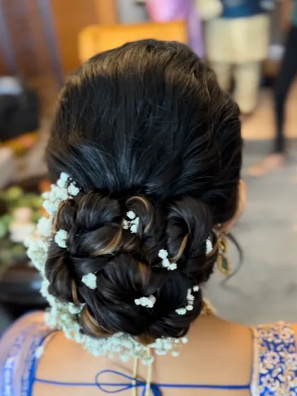 This is a soft, romantic messy bun intertwined with baby's breath. It's a dreamy and popular choice for receptions and engagements.