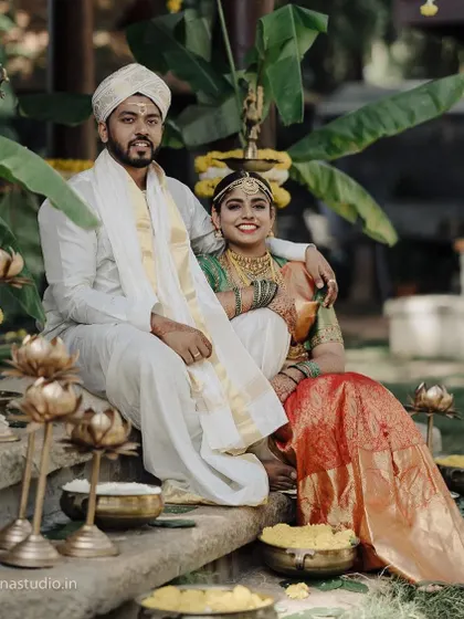 A classic portrait of a couple in their traditional wedding attire, seated on stone steps. The composition is balanced and elegant, highlighting their grace and the beauty of their surroundings.