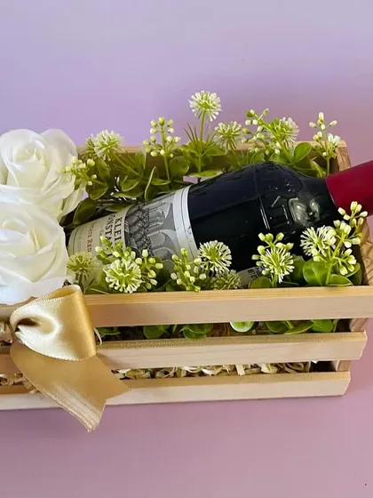 A simple and elegant wine presentation in a pinewood crate, adorned with white roses. This is a classic and sophisticated gift for any occasion.