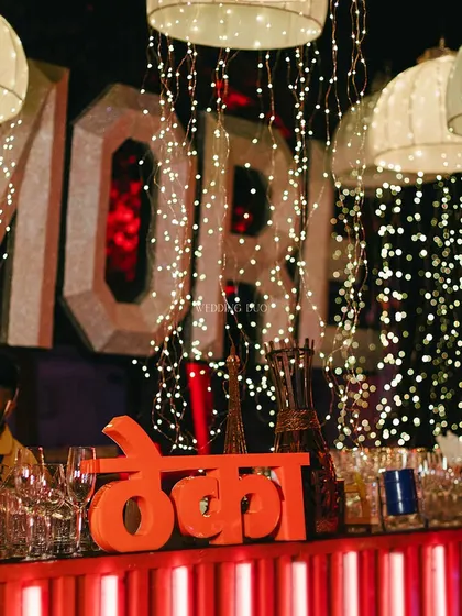 The 'Theka' is where the magic happens. This bar setup featured a fun, desi-inspired sign, set against a backdrop of cascading fairy lights and modern marquee letters for a playful yet chic cocktail experience.