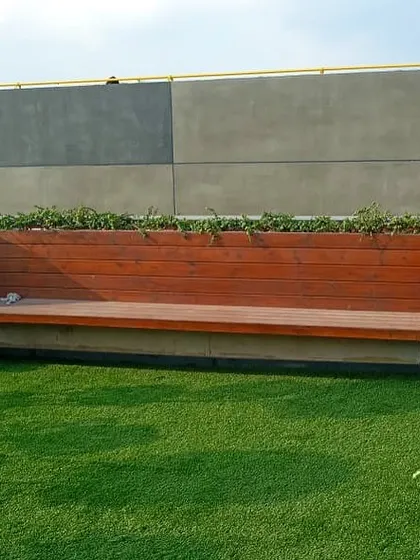 A custom-built wooden bench with integrated planters on either side. This functional piece provides seating while seamlessly incorporating greenery into the rooftop design.