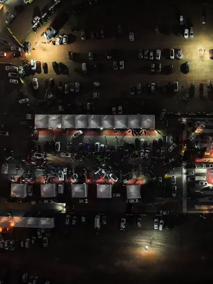 A top-down view of the illuminated expo area at night. This is the central hub of the festival, where brands, fans, and racers connect.