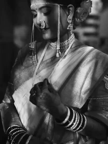 A moody black and white portrait that emphasizes the texture of the saree and the intricate jewelry, giving it a timeless, classic feel.