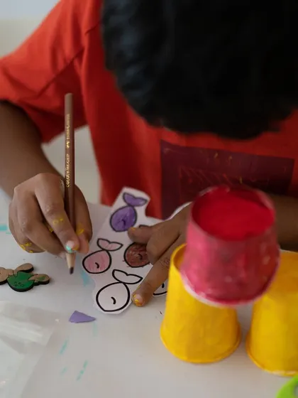 The start of a mixed-media masterpiece. Here, a child is carefully coloring fish cutouts that will become part of a larger 3D underwater scene. We use simple materials to create magical results.