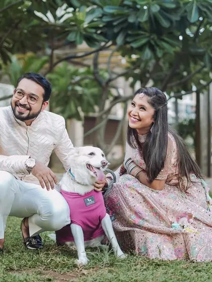A happy couple in elegant ethnic wear posing with their adorable dog in a green park. I love when couples bring their pets along, as it adds a personal and joyful touch to the pre-wedding photos.