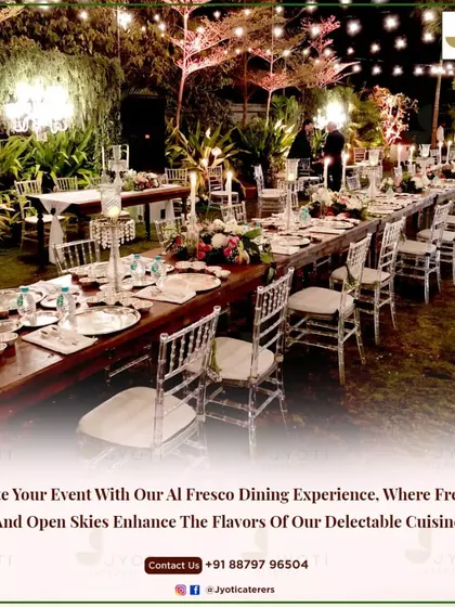A beautiful al fresco dining experience with a long wooden table set under a canopy of trees and twinkling lights, perfect for an intimate evening celebration.