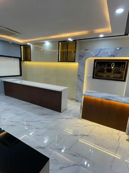 An overall view of the Lucknow office space. You can see how the reception, waiting area, and cabins are all tied together with a consistent theme of marble, wood, and smart lighting.