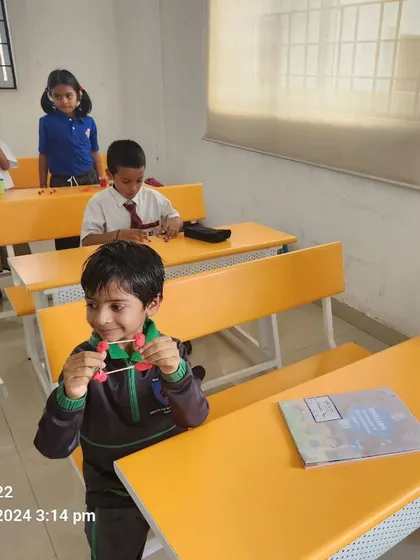 A student shows off the 3D shape he constructed during a math activity class. This hands-on experience brings geometry to life.