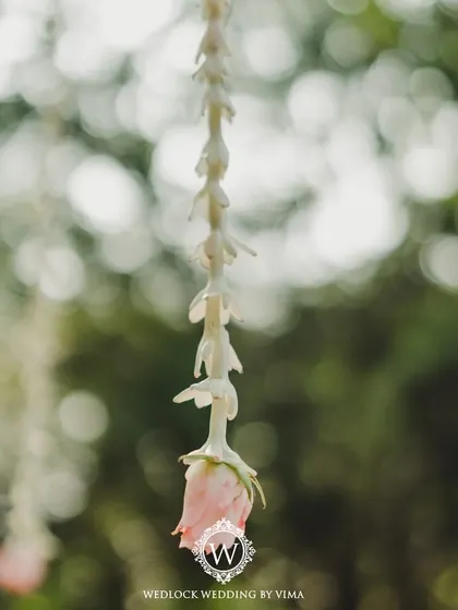 A single hanging floral tassel with a delicate pink rose. This close-up highlights the simple, meaningful details we incorporate to bring a couple's vision to life.
