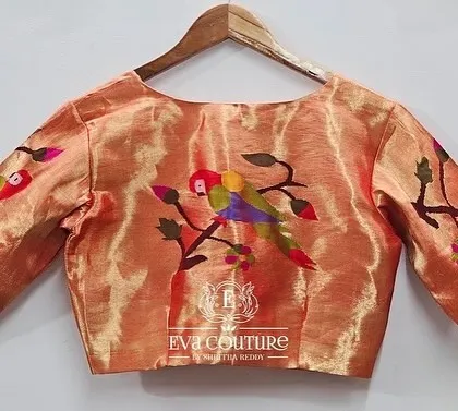 The back view of a pure Paithani handloom silk blouse. The sleeves and back feature colorful, woven parrot motifs, which can be customized in different colors.
