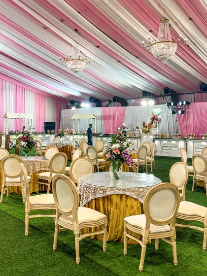 An ambiance of luxury. This beautiful marquee with pink and white draping, elegant seating, and crystal chandeliers creates a refined atmosphere for a daytime wedding celebration.