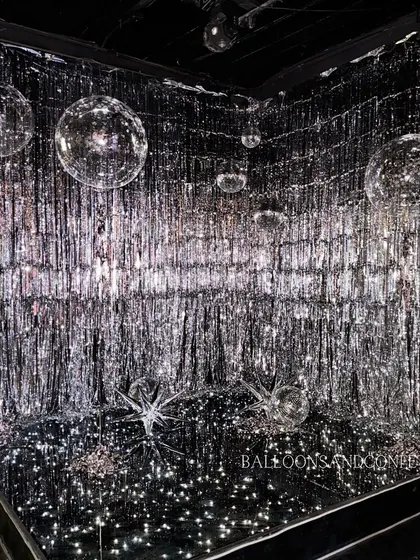 The final result of our glitter-filled photo booth. A silver fringe curtain, mirrored floor, and floating disco balls create a truly immersive and dazzling experience.