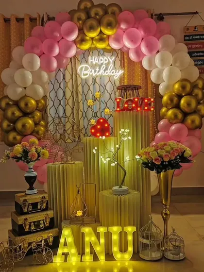 An elegant and romantic birthday decoration perfect for a surprise at home. The pink, white, and gold balloon arch, combined with light-up letters and props, creates a warm and celebratory feel.