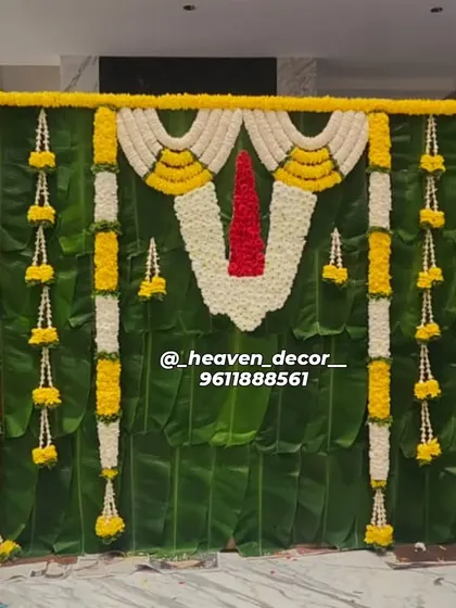 This backdrop is a tribute to South Indian tradition, crafted for a sacred ceremony. We used a full wall of fresh banana leaves, accented with garlands of jasmine and marigold, and a central floral 'Namam' to create an authentic and divine atmosphere.