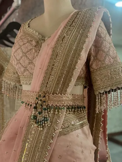 A beautiful pink saree with a matching embroidered blouse and a jeweled belt. The belt adds a modern touch and helps define the waist, a styling trick I often suggest to my clients.