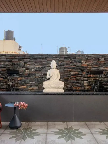 The terrace was designed for opulence and introspection, featuring a tranquil Buddha statue and a therapeutic water feature. The stacked stone wall and patterned floor tiles add texture and character to this outdoor sanctuary.