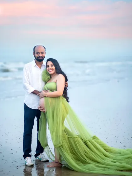 Standing at the water's edge, this couple looks serene and happy. The flowing green gown mimics the movement of the waves, creating a harmonious beach maternity portrait.