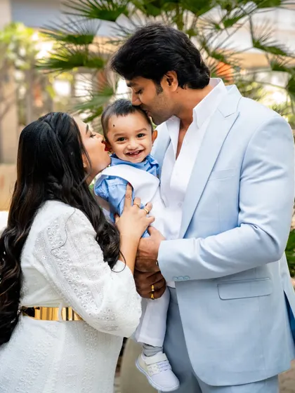 A beautiful family portrait from a first birthday celebration. The parents shower their little boy with kisses, creating a photo filled with love and happiness.