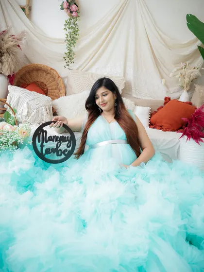 "Mommy to be." This beautiful announcement photo features the mom-to-be in a stunning light blue gown, surrounded by a dreamy setup.