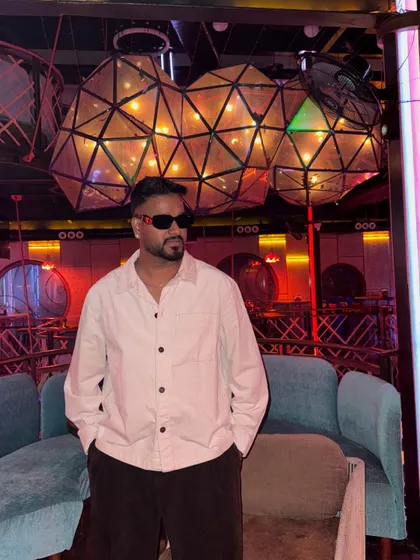 A candid shot in a club lounge with unique lighting. This captures the cool, relaxed vibe I embody before stepping behind the decks to turn up the energy.