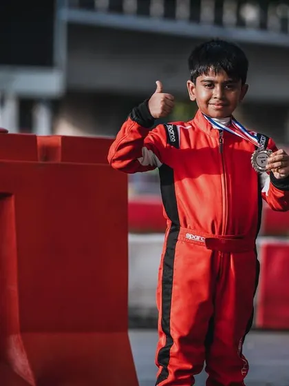 A young driver proudly shows off his medal after securing a podium finish at the Rok Cup in Singapore. It's a fantastic result from his international debut.