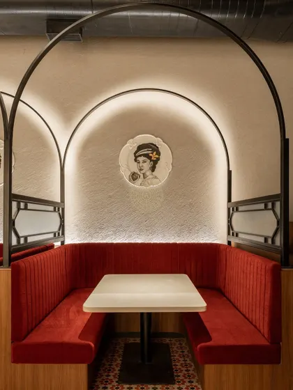 A cozy corner booth, perfect for an intimate meal. The custom plate art features a reimagined Goddess Flora, a nod to the original Flora Fountain location.
