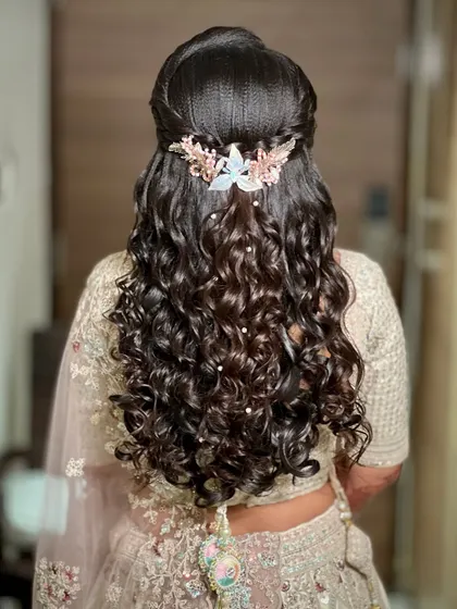 A detailed view of the half-up, half-down curly hairstyle, adorned with a delicate hair accessory.